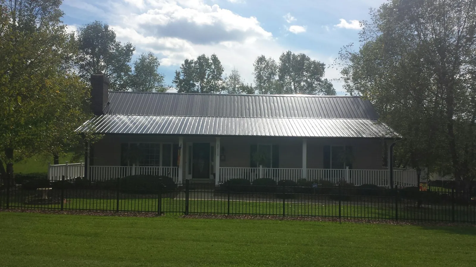 Gray metal roof on a brick ranch with a full width front porch — Gutter Guard Installation work by our crew in Tower City