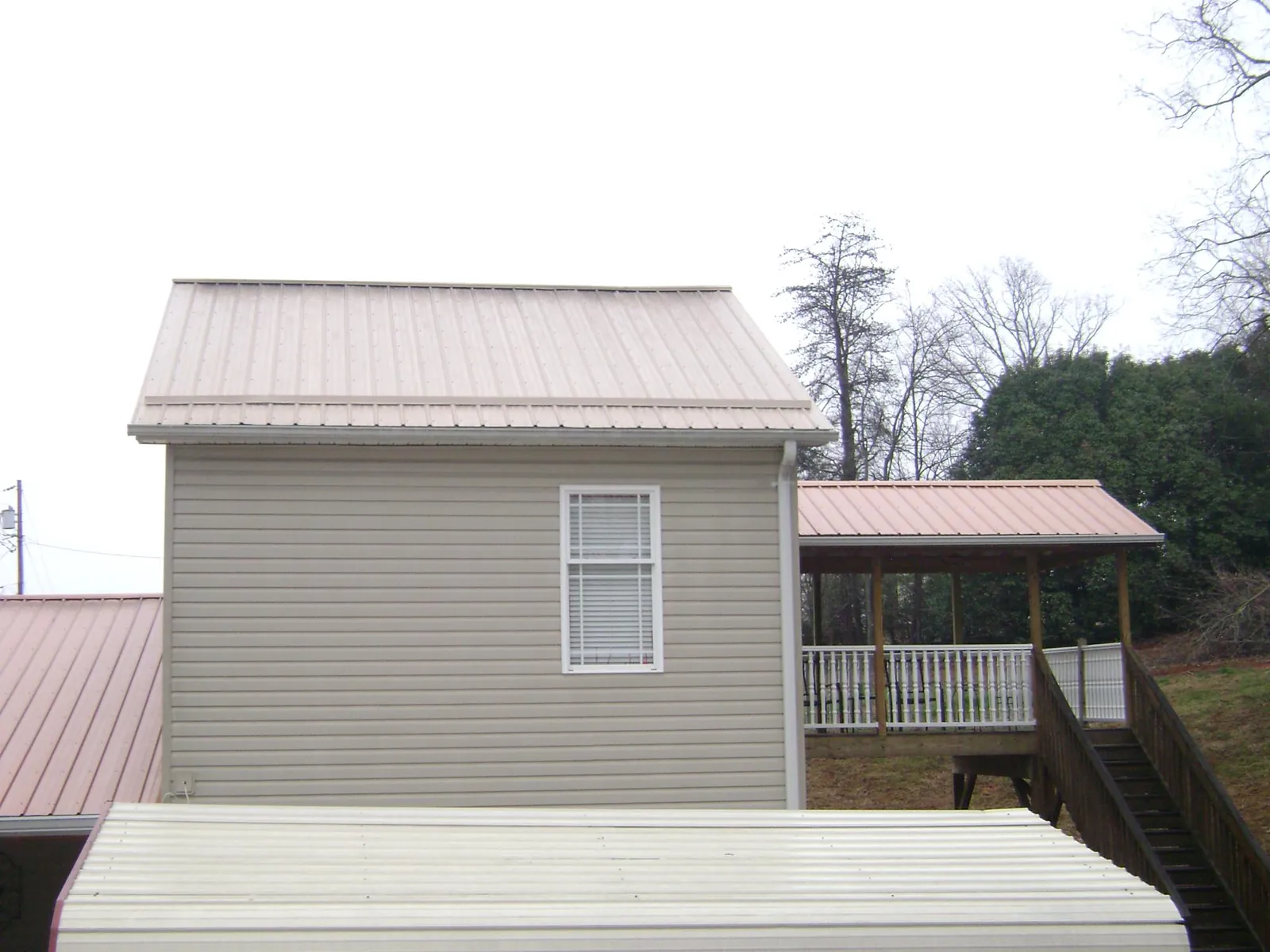 Tan metal roofs on a two story addition and attached porch, from a Roof Replacement job in Tower City